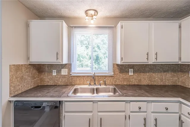 a kitchen with granite countertop a sink white cabinets and a window
