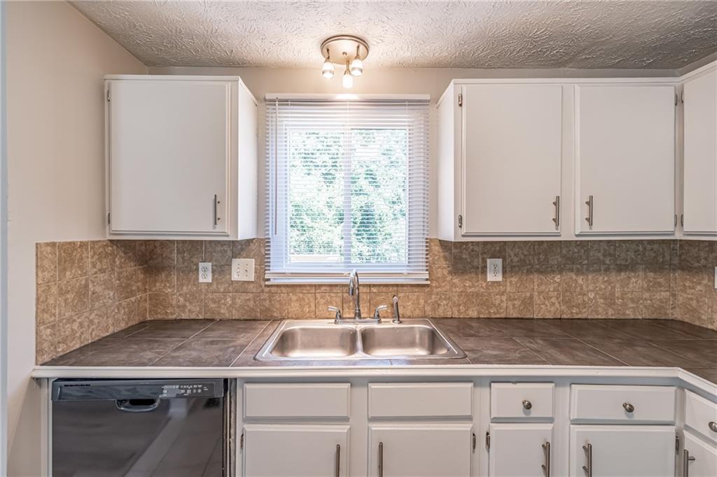 2407 Redfield Drive Norcross, GA 30071 - Photo 17 of 37 a kitchen with granite countertop a sink white cabinets and a window