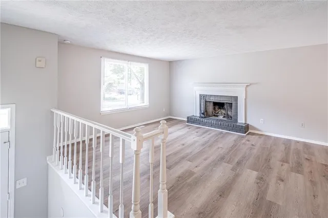 a view of empty room with fireplace and wooden floor