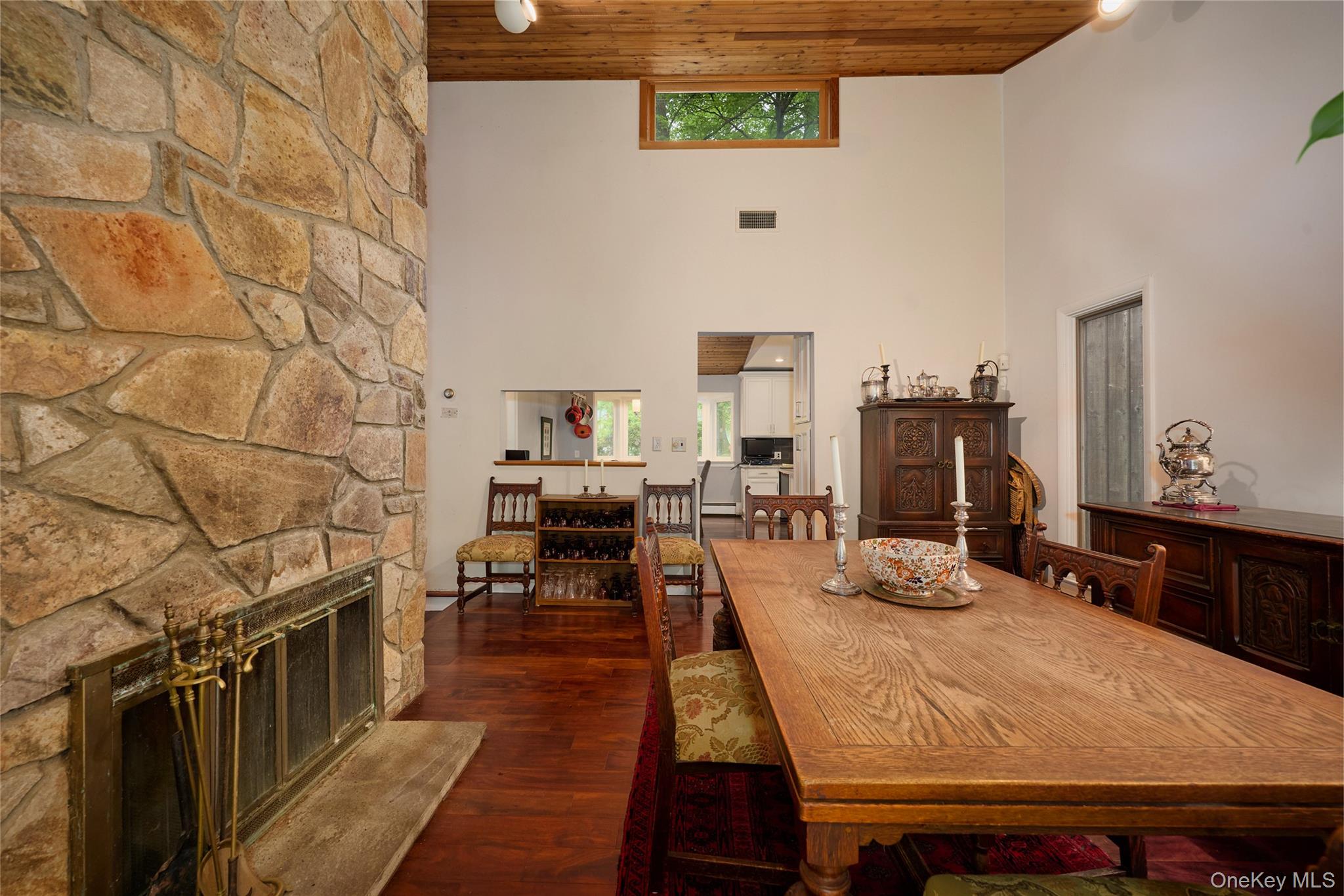 31 Greenlawn Road Katonah, NY 10536 - Photo 12 of 47 Dining room featuring wooden ceiling, a stone fireplace, a towering ceiling, and dark wood-type flooring