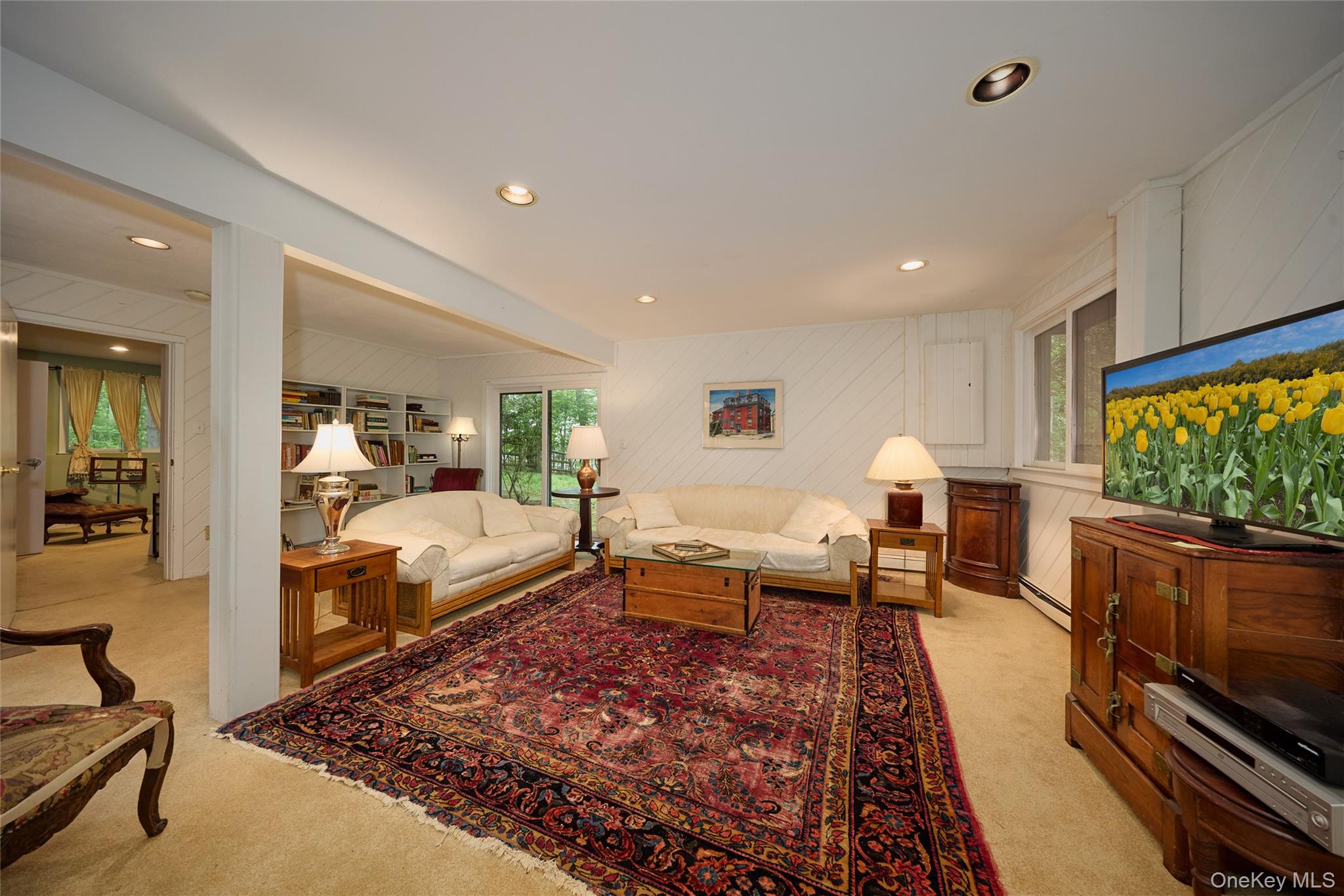 31 Greenlawn Road Katonah, NY 10536 - Photo 24 of 47 Living room featuring light colored carpet, a baseboard heating unit, recessed lighting, and wooden walls