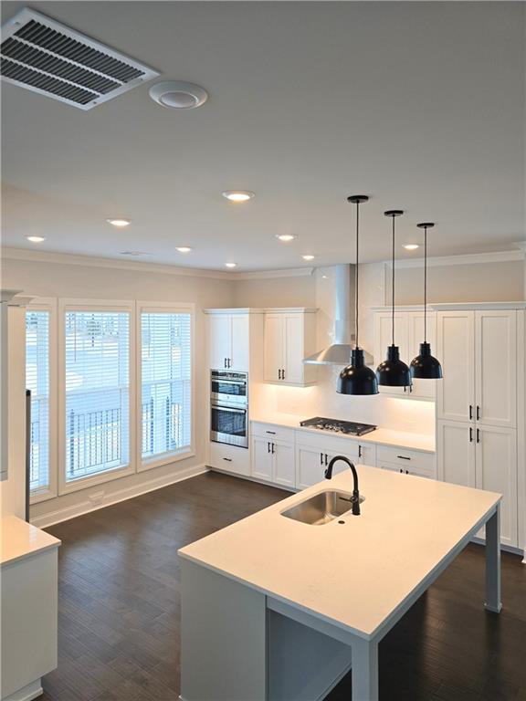 163 Basil Street Cumming, GA 30040 - Photo 14 of 56 a open kitchen with kitchen island a stove a sink and white cabinets with wooden floor