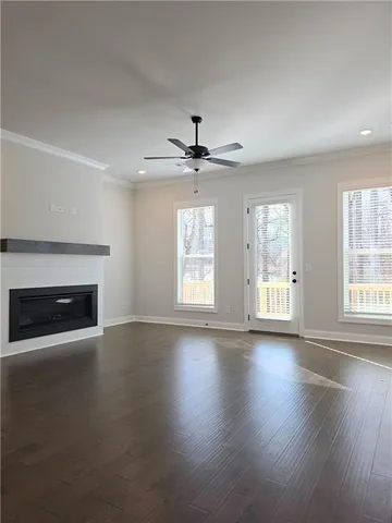 an empty room with wooden floor fireplace and windows
