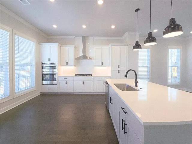 a large kitchen with stainless steel appliances a large counter top a stove a chimney a sink and a window