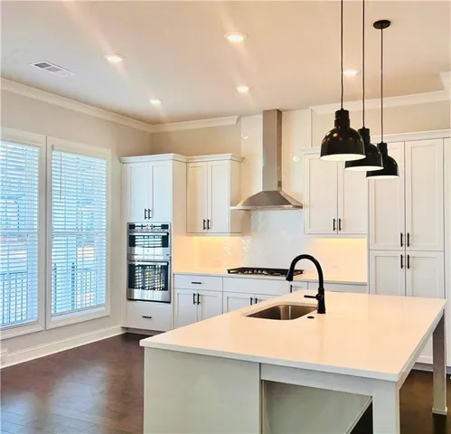a kitchen with stainless steel appliances a sink a stove and a wooden floor
