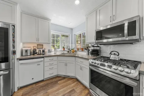 a kitchen with stainless steel appliances granite countertop a stove a sink dishwasher a microwave oven with cabinets and wooden floor