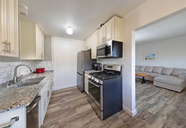a kitchen with stainless steel appliances granite countertop a sink stove and refrigerator