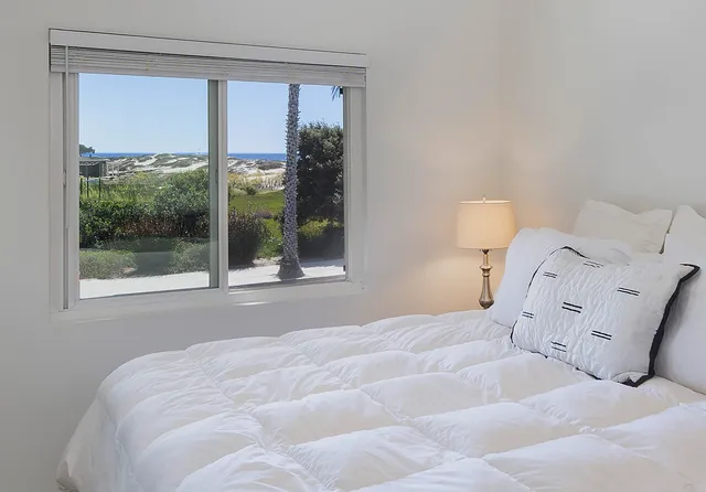 a large white bed sitting in a bedroom next to a window