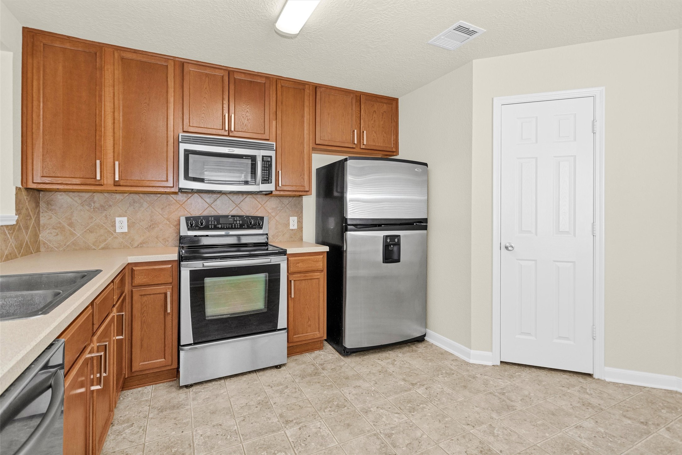 3131 Beacon Grove Street Spring, TX 77389 - Photo 14 of 38 a kitchen with granite countertop a refrigerator stove and microwave
