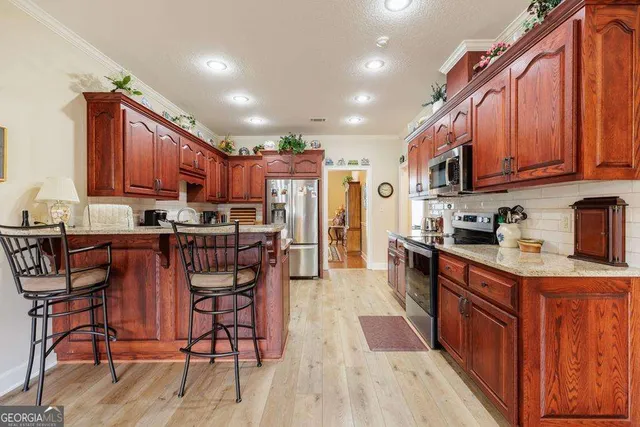 a kitchen with stainless steel appliances granite countertop wooden cabinets a refrigerator and a stove top oven