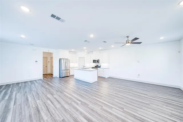 a large white kitchen with kitchen island a sink dishwasher a stove and white cabinets with wooden floor