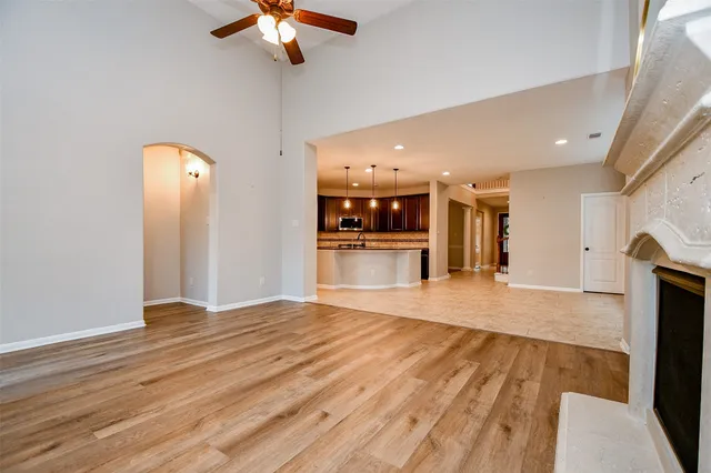 a view of empty room with wooden floor and fan