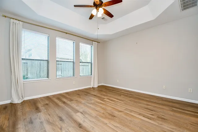 wooden floor in an empty room with a chandelier fan