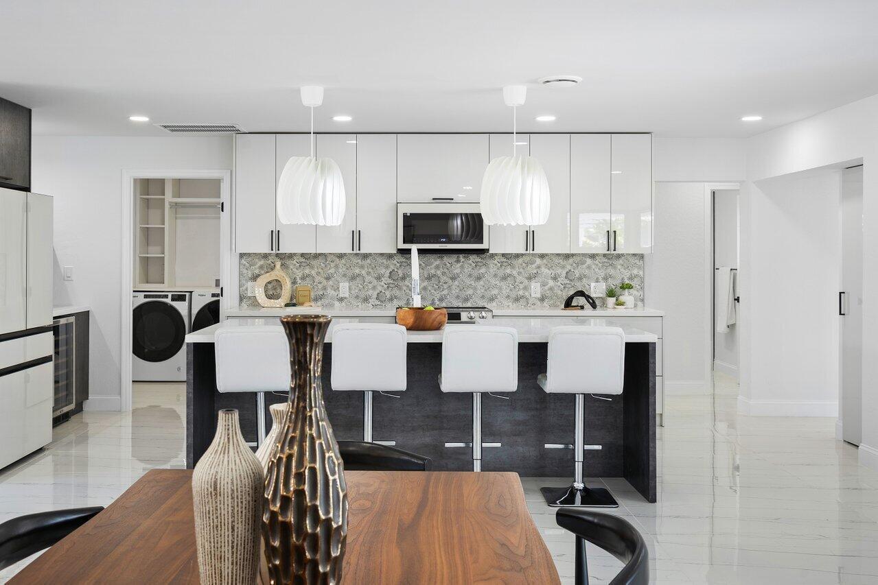 1200 Southwest 8th Street Boca Raton, FL 33486 - Photo 12 of 42 a kitchen with stainless steel appliances kitchen island granite countertop a stove a sink a microwave a dining table and chairs