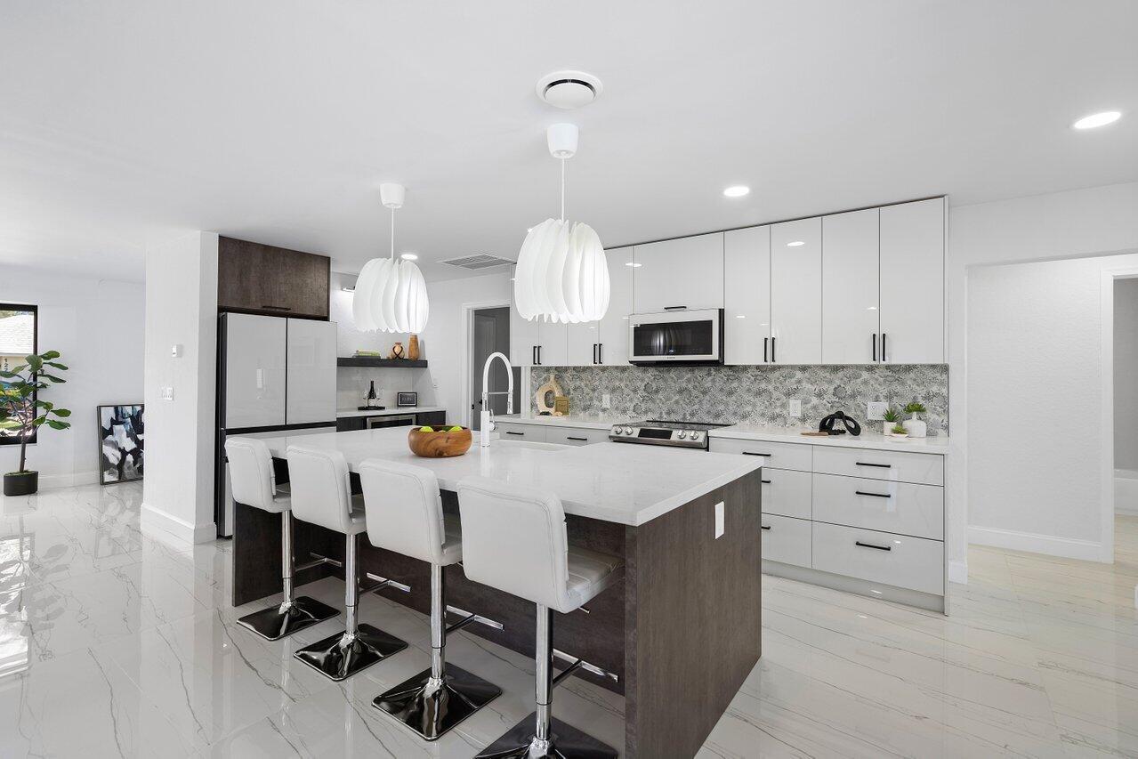 1200 Southwest 8th Street Boca Raton, FL 33486 - Photo 15 of 42 a kitchen with kitchen island granite countertop a sink a counter space stainless steel appliances and cabinets