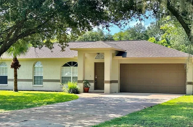 a front view of a house with a garden and a tree