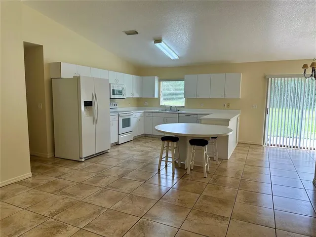 a kitchen with stainless steel appliances kitchen island granite countertop a refrigerator a sink a dining table and chairs