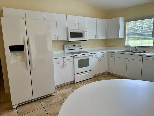a kitchen with white cabinets and white appliances