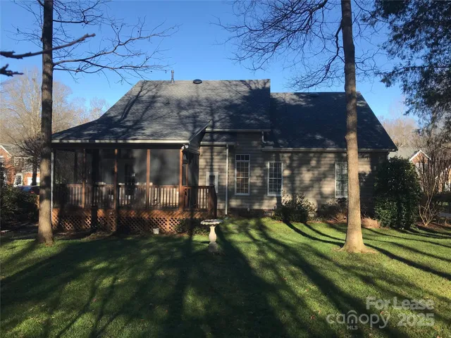 a view of a house that has a small yard and large trees