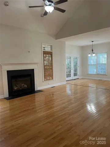 an empty room with wooden floor fireplace and windows