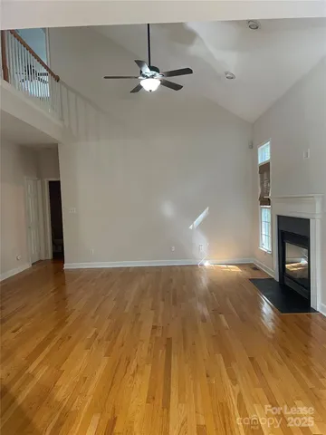 a view of an empty room with wooden floor and a fireplace