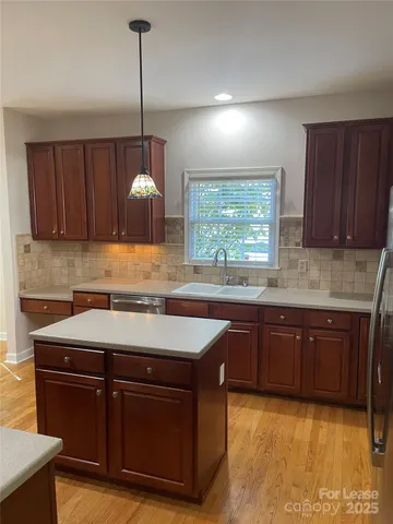 a kitchen with a stove a sink a window and cabinets