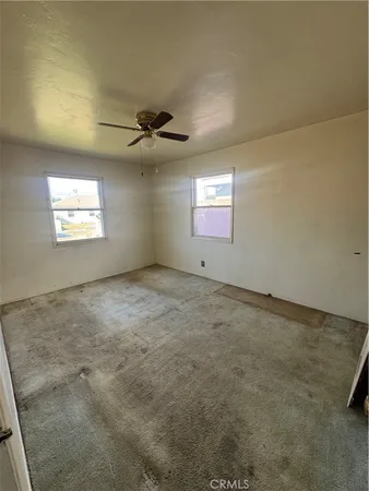 an empty room with windows and ceiling fan view