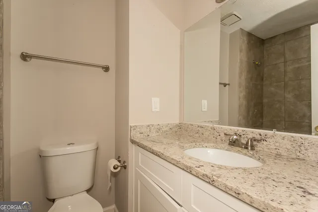 a bathroom with a granite countertop sink toilet and shower