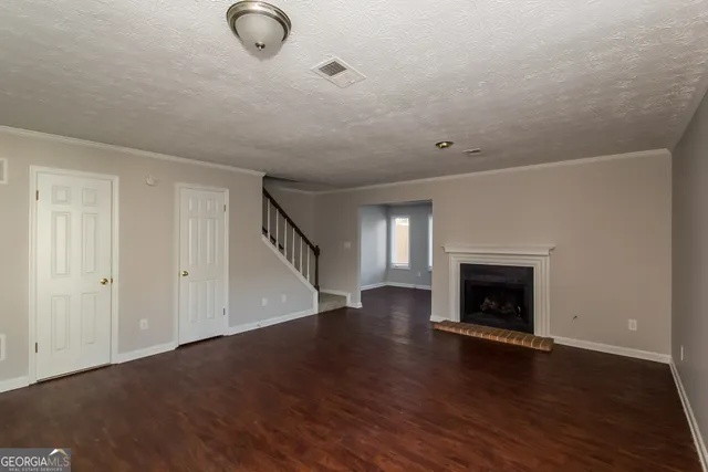 a view of an empty room with wooden floor fireplace and a window