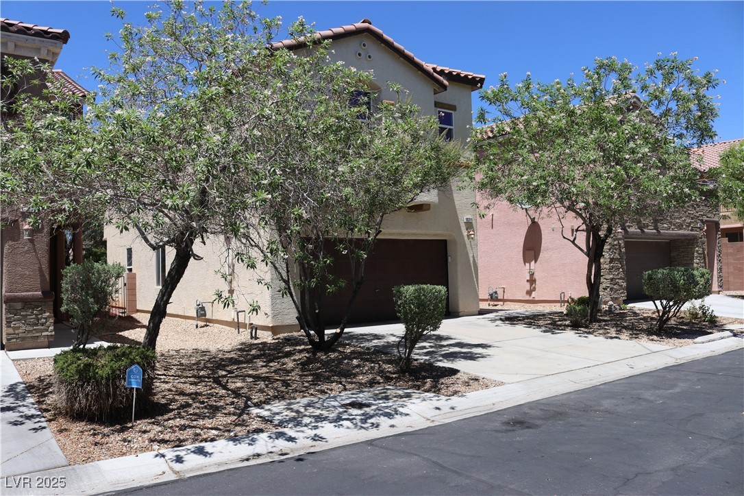 10211 Glimmering Star Drive Las Vegas, NV 89178 - Photo 2 of 33 View of front of house featuring an attached garage, concrete driveway, a tiled roof, and stucco siding