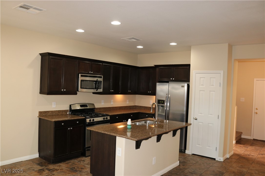 10211 Glimmering Star Drive Las Vegas, NV 89178 - Photo 4 of 33 Kitchen with stainless steel appliances, recessed lighting, dark stone countertops, a breakfast bar, and a center island with sink