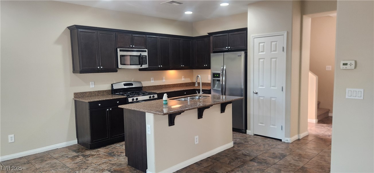 10211 Glimmering Star Drive Las Vegas, NV 89178 - Photo 6 of 33 Kitchen with stainless steel appliances, dark stone counters, a breakfast bar area, dark cabinetry, and recessed lighting