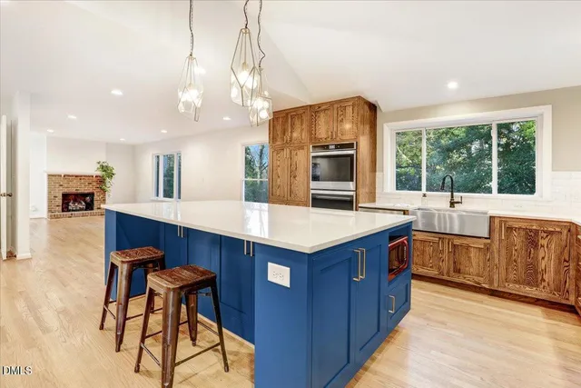 a kitchen with stainless steel appliances granite countertop wooden cabinets a stove a sink and a large window