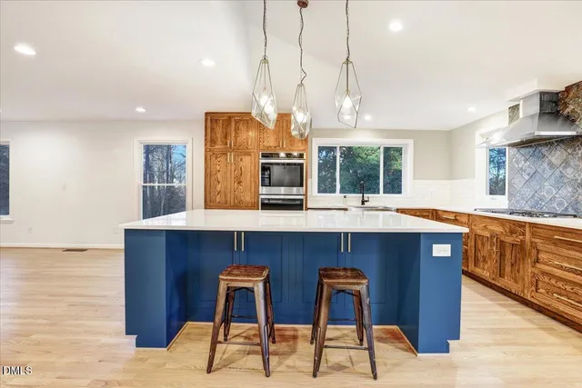 a kitchen with stainless steel appliances kitchen island granite countertop a table chairs sink and cabinets
