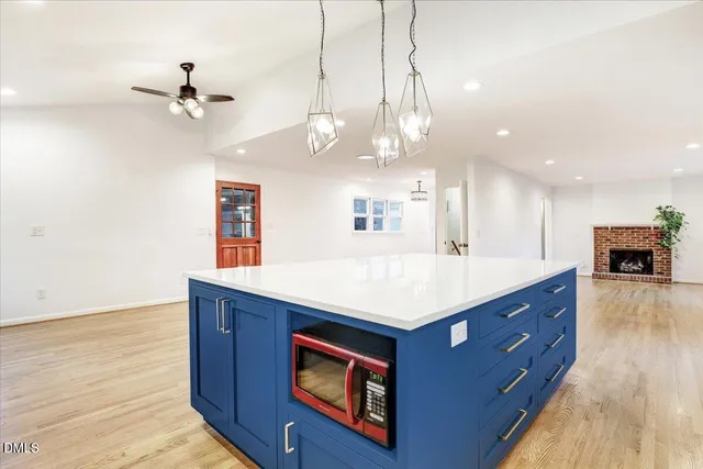 a view of kitchen with stainless steel appliances kitchen island wooden cabinets and fireplace