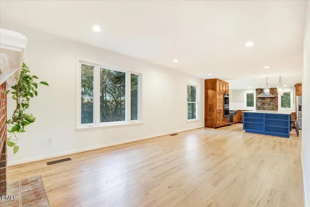 an empty room with wooden floor fireplace and windows