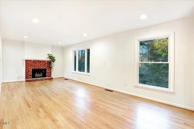 an empty room with wooden floor chandelier fan and windows