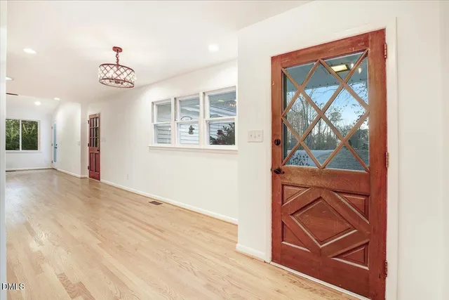an empty room with wooden floor cabinet and windows