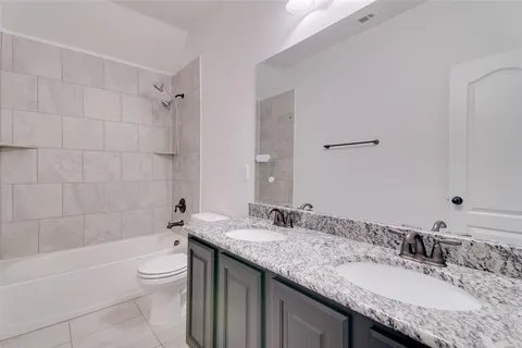 a bathroom with a granite countertop bathtub sink vanity mirror and toilet