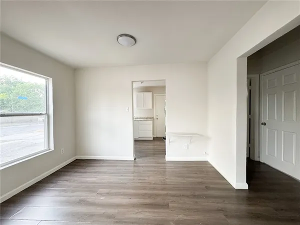 a view of an empty room and wooden floor and a window