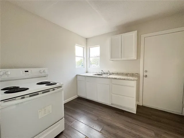 a kitchen with granite countertop white cabinets and white appliances