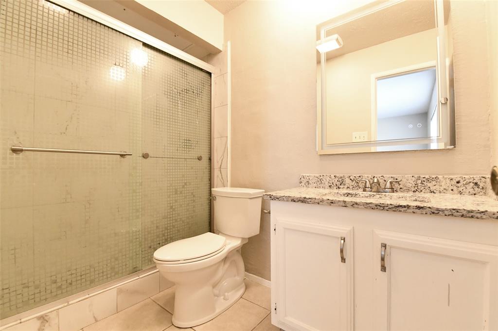 4113 Juneberry Street Fort Worth, TX 76137 - Photo 27 of 36 a bathroom with a granite countertop sink toilet a mirror and a shower