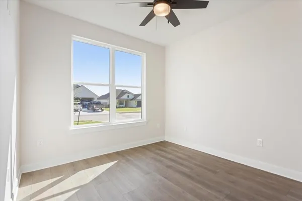 an empty room with wooden floor fan and windows