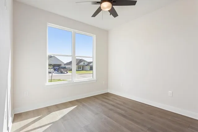an empty room with wooden floor fan and windows