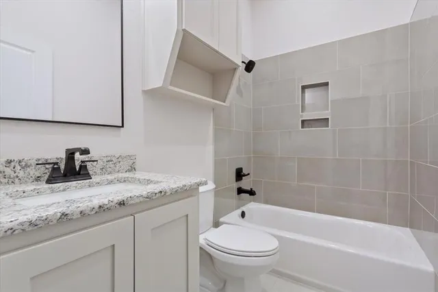 a bathroom with a granite countertop sink a toilet and bathtub