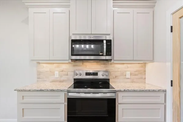 a kitchen with stainless steel appliances granite countertop white cabinets and a stove