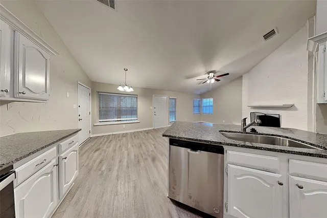 a kitchen with kitchen island granite countertop a sink cabinets and wooden floor