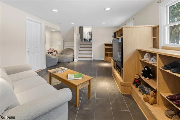 a living room with furniture a flat screen tv and a refrigerator