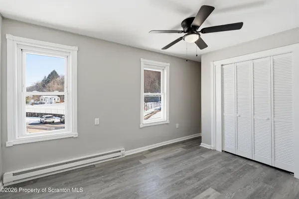 a view of empty room with wooden floor and fan