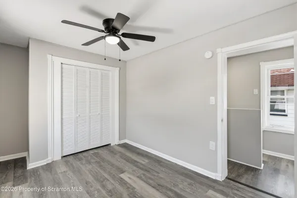 a view of empty room with wooden floor and ceiling fan